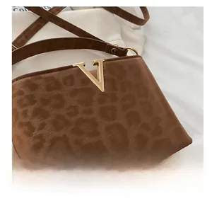 Close-up of leopard print crossbody bag with gold V-shaped hardware and soft suede texture