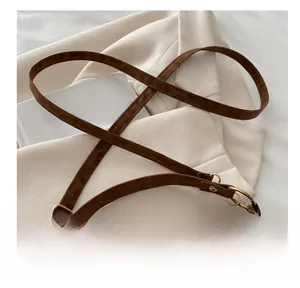 Detail of the brown suede shoulder bag featuring a prominent gold V-shaped metal logo
