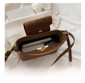 Internal view showing storage capacity of brown suede shoulder bag with V-shaped metal trim