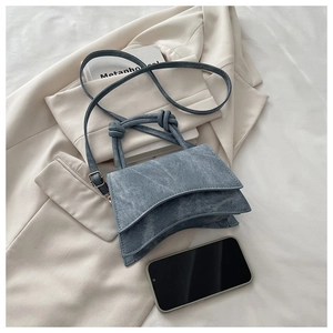Blue denim crossbody bag with unique double flap design and knot handle details