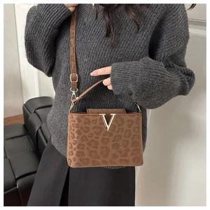 Détail du sac léopard avec boucle en V dorée porté sur un pull gris foncé