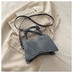 Detail of grey-blue crossbody bag with denim texture and decorative knotted handle