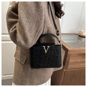 Détail du sac à bandoulière léopard avec boucle V dorée et matière en suède texturé
