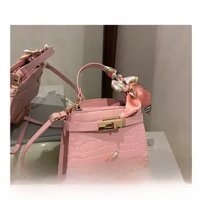 Close-up of pink faux crocodile leather handbag with silk scarf handle and metal clasp