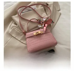 Detailed view of pink croc-effect square bag with gold lock and floral silk scarf
