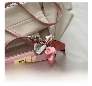 Detailed close-up of pink croc-embossed leather handbag with gold clasp and silk scarf