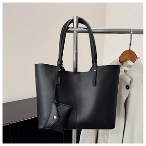 Detail of a black matte leather tote bag with gold hardware and matching pouch