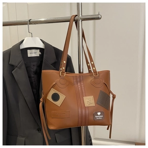 Detail view of large brown leather tote bag with patchwork and shoulder strap