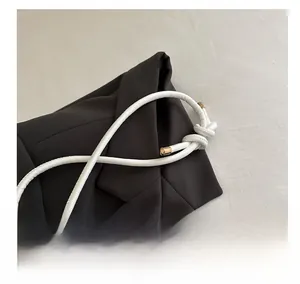Détail de la bandoulière en corde nouée blanche avec embouts dorés sur sac à main noir