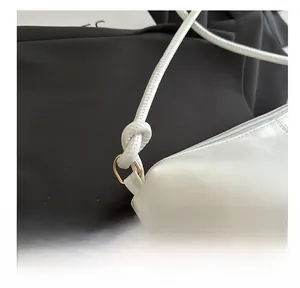 Détail du sac en cuir blanc montrant la bandoulière nouée et l'anneau en D doré