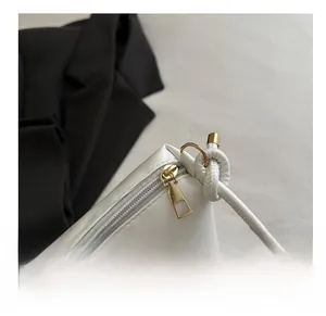 Détail de la fermeture éclair dorée et du nœud sur un sac cabas blanc en cuir minimaliste