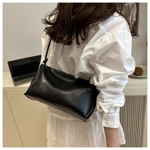 Minimalist black leather shoulder bag styled on person in a bright office setting