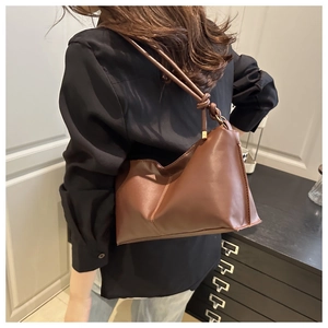 Side view of a brown minimalist leather shoulder bag with a stylish knot strap detail
