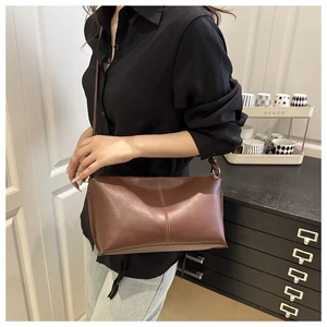 Détail du sac à main en cuir marron avec coutures verticales et finitions dorées