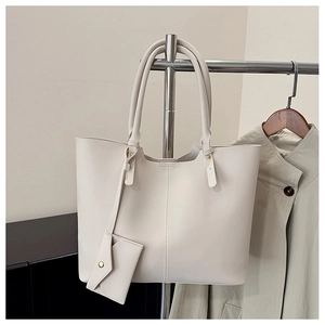 Detail of a large beige tote bag with a small matching pouch hanging on a metal hanger