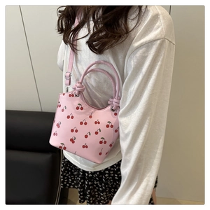 Detail of pink bucket bag with cherry print, dual ring handles and thin shoulder strap