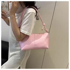 Detail view of a pink minimalist underarm bag with knot strap and golden hardware accents
