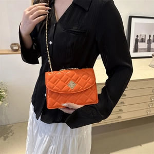 Borsa a tracolla trapuntata arancione con catena dorata indossata da una modella