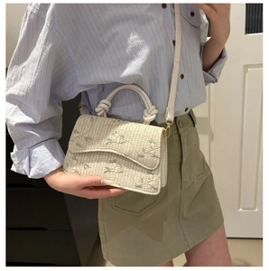 Detail of floral embroidery on cream woven crossbody bag with thick rope handle