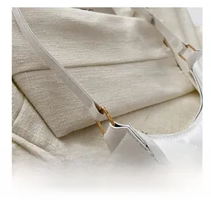Détail de la texture cuir matelassé blanc et de l'anneau en D doré sur le sac à bandoulière