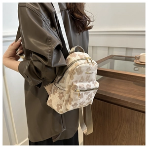 Détail d'un mini sac à dos beige pour femme avec motifs floraux vintage et poche zippée avant