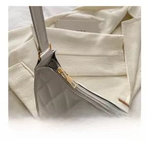 Détail de la fermeture éclair dorée et des coutures matelassées sur le sac blanc