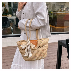 Detail of woven straw shoulder bag with white lace bow and rainbow accents