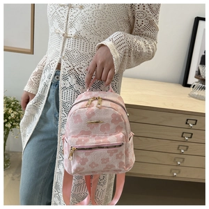 Detail of pink floral embroidery on a mini backpack with golden zipper and fabric straps