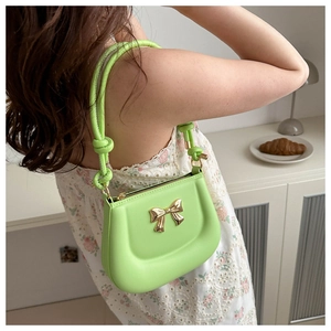 Detail of fruit green leather underarm bag with gold bow buckle and knotted strap
