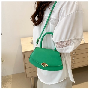 Sacoche demi-lune verte en cuir avec boucle dorée portée sur un haut en dentelle blanche