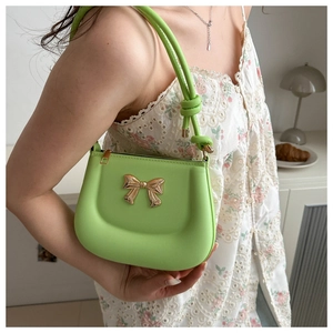 Detail of light green leather shoulder bag with a gold bow and stylish knot strap