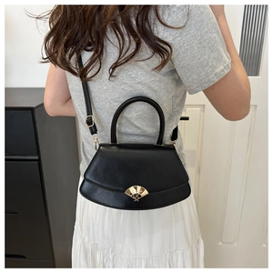Sac à main chic en cuir noir en forme d'éventail avec boucle dorée porté par un mannequin