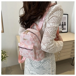 Detail eines rosa geblümten Mini-Rucksacks mit Goldbeschlägen und mehreren Fächern