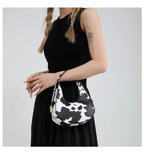 Close-up of cow print hobo bag showing texture and adjustable metal buckle strap