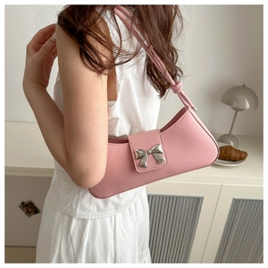 Elegante borsa baguette rosa con fiocco argento indossata da una modella in stile casual