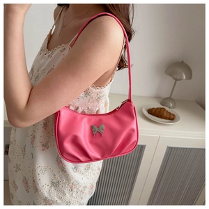 Vue détaillée du sac sous l'aisselle plissé rose vif avec boucle papillon en métal argenté