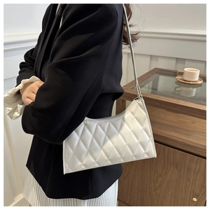 Gros plan sur le sac sous le bras blanc matelassé avec motif losanges porté par un modèle