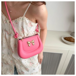 Detail of fuchsia mini saddle bag with gold bow clasp and decorative knot strap
