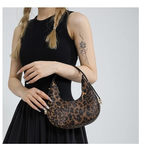 Detail of trendy leopard print crescent bag with black handles and gold hardware accents