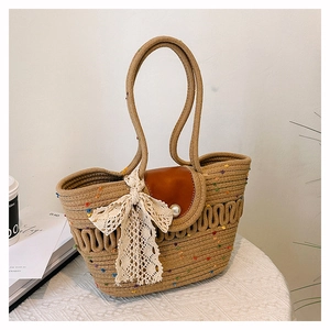 Détail d'un sac tressé avec rabat en cuir, boucle en perle et nœud en dentelle élégant