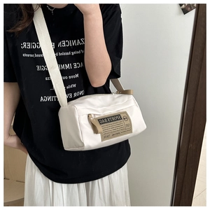 Mirror selfie showing a white nylon crossbody pillow bag with sports bag patch