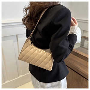 Vue détaillée du sac à bandoulière matelassé beige porté par un mannequin