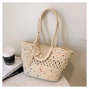 Détail d'un sac cabas en paille avec boucle perle et nœud en dentelle élégant