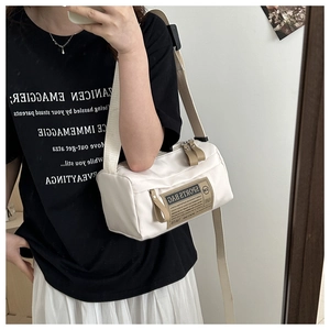 Mirror selfie showing a white cylindrical canvas sports crossbody bag with strap detail