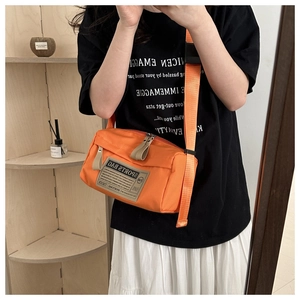 Detail of the orange oxford fabric sports bag with adjustable strap and brand tag