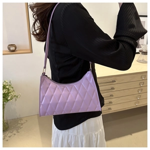 Sac bandoulière lilas à motif matelassé porté pour illustrer le style et la coupe