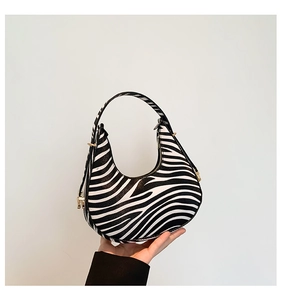 Detail of zebra print crescent bag with golden zipper and textured leather finish