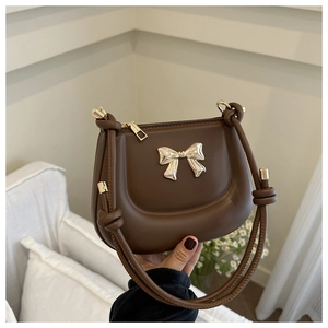 Detail of coffee brown underarm bag with golden bow buckle and knotted shoulder strap