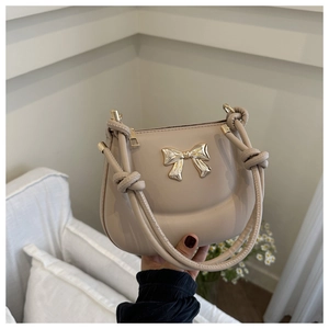 Detail of light beige faux leather handbag with gold bow and unique rope straps