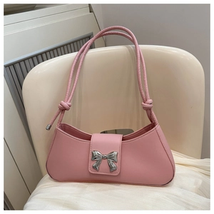 Detailed shot of pink underarm bag featuring a silver metal bow and decorative shoulder straps